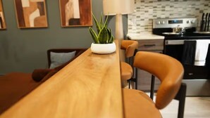 Una cocina moderna con una mesa de madera, sillas y una planta en maceta.