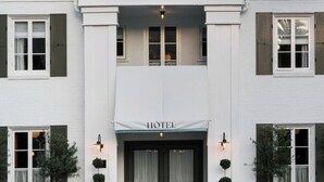 A white hotel with a central entrance, double doors, and a sign above the doors. - The Hotel Lili - Beverly Hills (Beverly Hills)