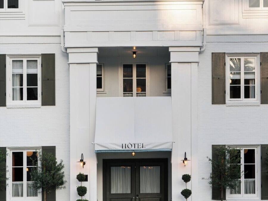 A white hotel with a central entrance, double doors, and a sign above the doors.