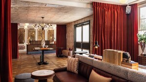 A cozy lounge area with a sofa, ottomans, a round table, and a decorative vase. - The Hotel Lili - Beverly Hills (Beverly Hills)