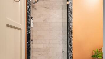 A bathroom with a shower, a sink, and a towel rack.
