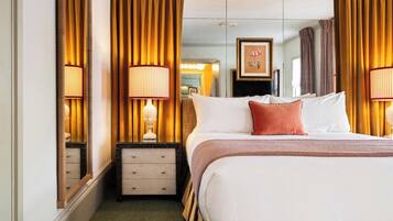 A hotel room with a large bed, two bedside lamps, a dresser, a mirror, and a framed picture on the wall.