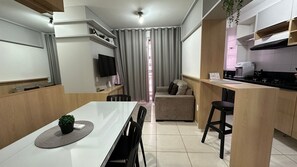 A modern kitchen with a dining area, a TV, and a kitchen island.