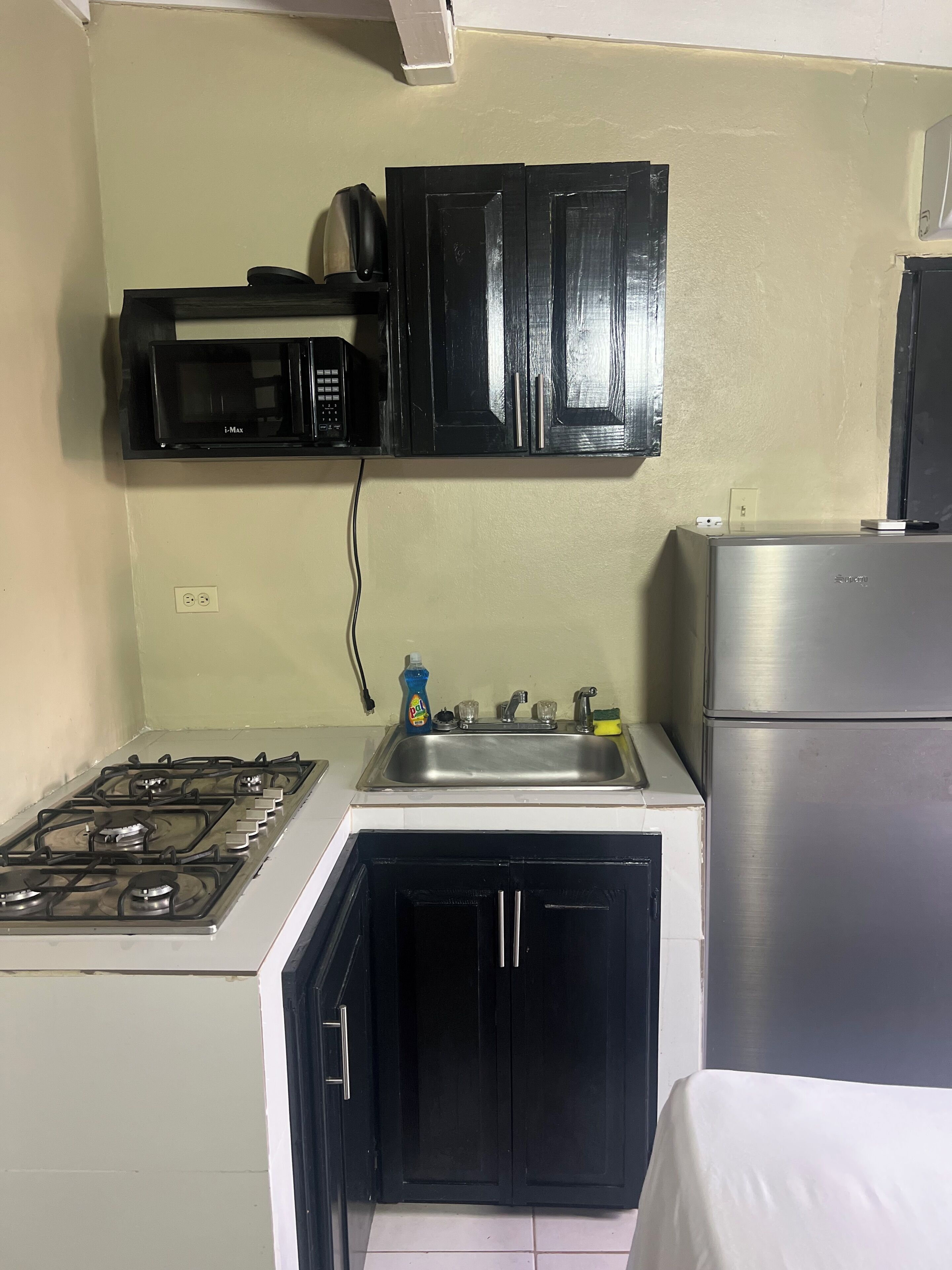 Una cocina compacta con estufa a gas, un lavamanos, un microondas y un refrigerador.