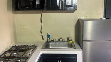 Una cocina compacta con estufa a gas, un lavamanos, un microondas y un refrigerador.