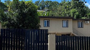 Un edifici residencial amb façana color beix, una reixa de metall negre i un cel blau clar.