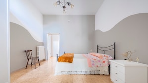 Ein Schlafzimmer mit Bett, Sessel, Kommode und einer Chandelier.