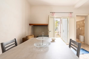 A dining table with a glass cake stand, chairs, and a view of the outside.