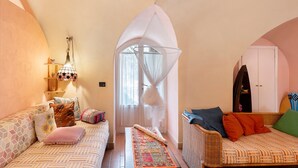 A cozy room with a sofa, a small table, a decorative lamp, and a wardrobe. - Holiday Home 'Piccolo Angolo di Paradiso' with Private Terrace, Garden & Wi-Fi (Taggia)