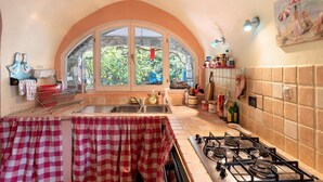 A kitchen with a gas stove, a sink, and a window overlooking greenery. - Holiday Home 'Piccolo Angolo di Paradiso' with Private Terrace, Garden & Wi-Fi (Taggia)
