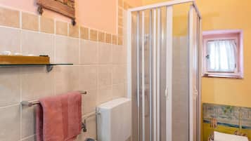 Un baño con inodoro, ducha, toallero y ventana con cortina.