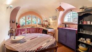 A kitchen with a checkered tablecloth, a window with a view of greenery, and a purple cabinet. - Holiday Home 'Piccolo Angolo di Paradiso' with Private Terrace, Garden & Wi-Fi (Taggia)