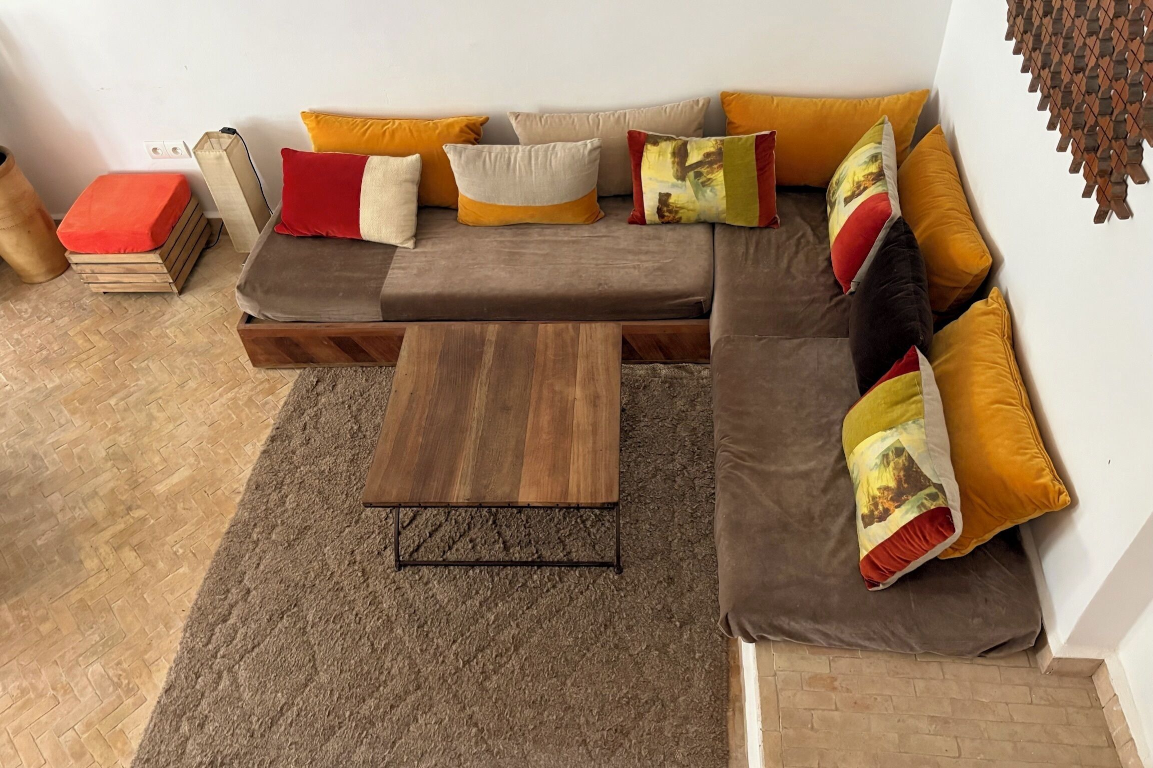 Un canapé modulable avec plusieurs coussins, une table basse en bois et un parquet à motifs chevrons.
