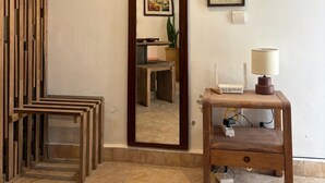 Una stanza con un divisorio in legno, un ampio specchio, un tavolino con una lampada e un certificato incorniciato appeso al muro.