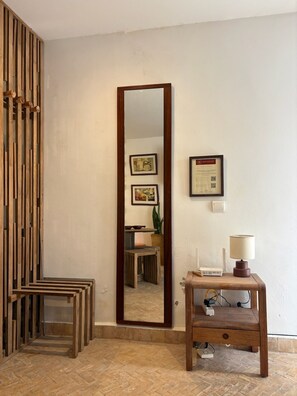 A room with a wooden partition, a large mirror, a small table with a lamp, and a framed certificate on the wall. - Dar Sghira - House in the heart of Essaouira with sunny terrace (Essaouira)