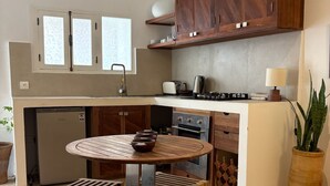 Una cucina compatta con mobili in legno, un forno integrato, un tavolo da pranzo rotondo e una pianta in vaso.