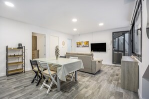 Un salon moderne avec une table à manger, un canapé et un téléviseur.