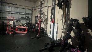 A gym with various exercise equipment, including a squat rack, dumbbells, and weight plates. - Cozy 1-bedroom house with AC in quaint Houston neighborhood (Houston)