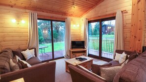 A cozy living room with a wooden interior, a flat-screen TV, and a sliding glass door leading to a deck.
