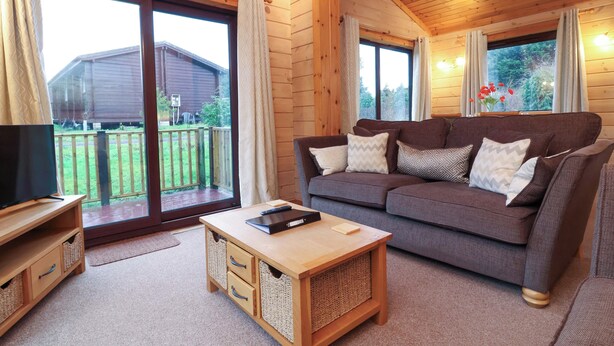 A cozy living room with a sofa, a coffee table, and a TV on a wooden stand. There are wicker baskets under the coffee table and a wooden cabinet with drawers.