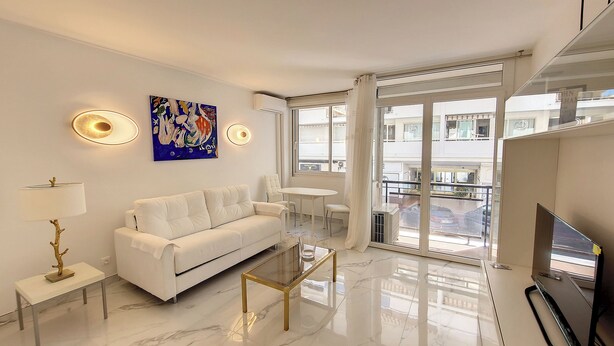 A modern living room with a white sofa, a glass coffee table, and a painting on the wall. - HENRI CAMILLE AGENCY- Croisette - 2 bedrooms, 2 Bathrooms, 50m Croisette (Cannes)