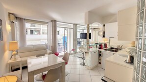 A modern hotel room with a dining area, kitchenette, and a large window offering a view of the city. - HENRI CAMILLE AGENCY- Croisette - 2 bedrooms, 2 Bathrooms, 50m Croisette (Cannes)