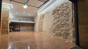 A spacious room with a tiled floor, stone walls, and a ceiling light fixture. - MIRADOR DEL TORREÓN (Alcañiz)