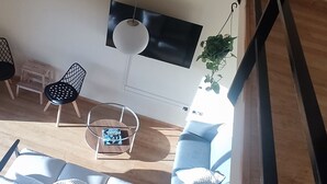 A modern living room with a sofa, chairs, a coffee table, and a hanging plant. - MIRADOR DEL TORREÓN (Alcañiz)