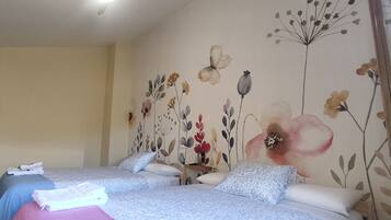 Un dormitorio con dos camas, una escalera de madera y un muro con motivos florales.