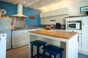 Eine moderne Küche mit weißen Schränken, einer Holzinsel und blauen Hocker.