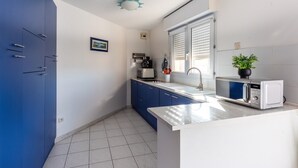 Eine moderne Küche mit blauen Schränken, einer weißen Arbeitsplatte und einer Mikrowelle.