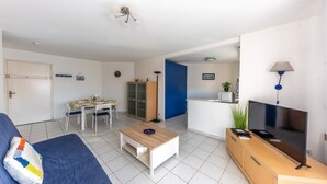 Ein Wohnzimmer mit einer Couch, Couchtisch, Fernseher und einem Essbereich mit Stühlen und Tisch.