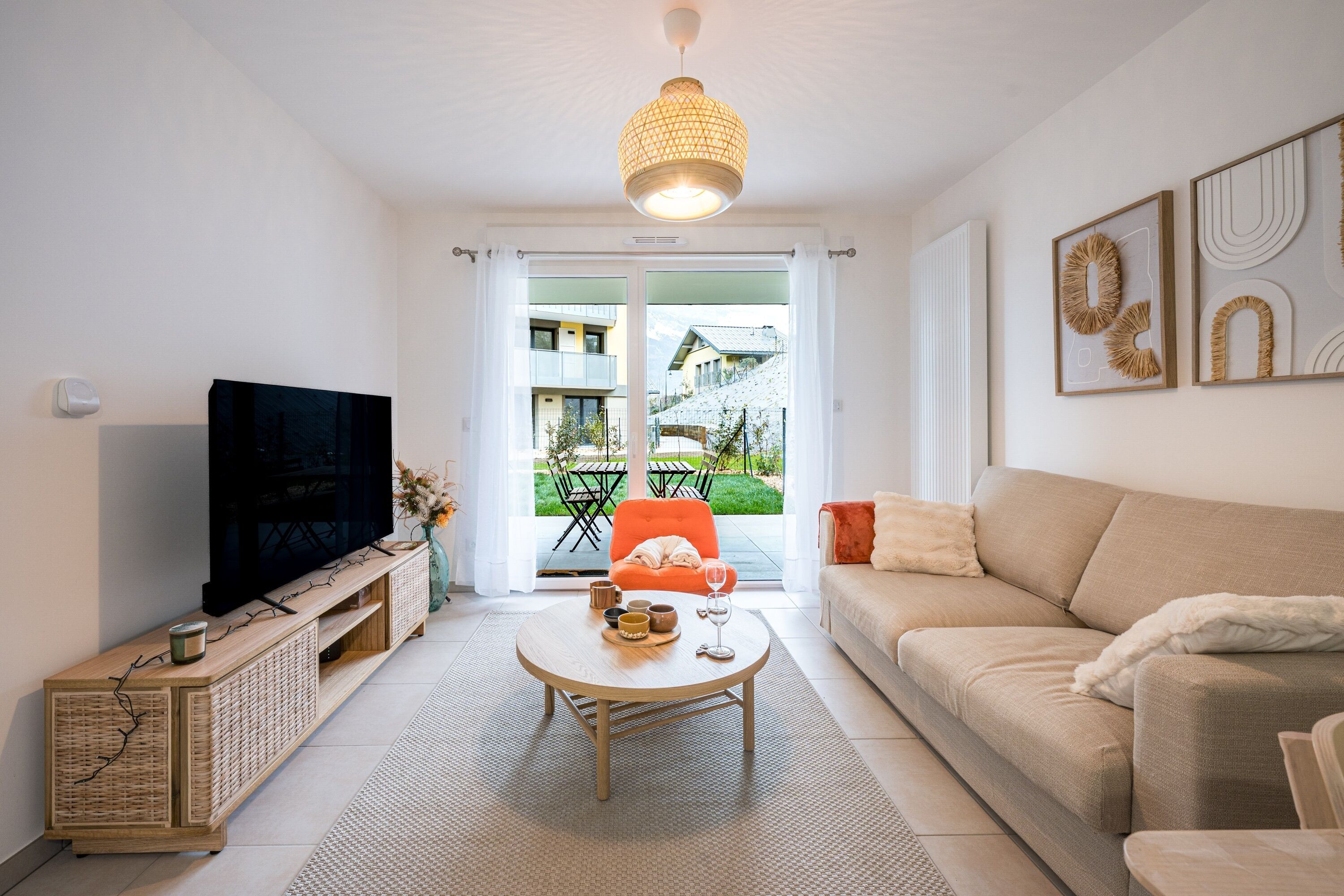 A modern living room with a television, sofa, coffee table, and a view to the outside.