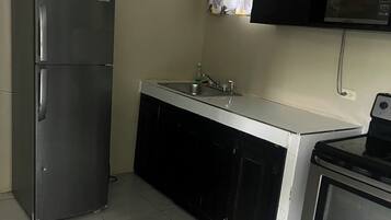 A compact kitchen with a refrigerator, a microwave, and an oven.