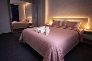 A modern hotel room with a large bed, a mirror, and a nightstand with a lamp. - Charming T2 for 4 people, private parking, 10 min from metro, (Toulouse)