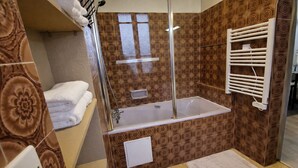 A bathroom with a bathtub, a shower, a towel rack, and a patterned wall.