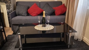 A modern living room with a glass-top coffee table, a bottle of champagne, and two glasses.
