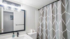 A bathroom with a white sink, a mirror, a toilet, and a shower curtain with a geometric pattern. - Dwell (Scottsdale)