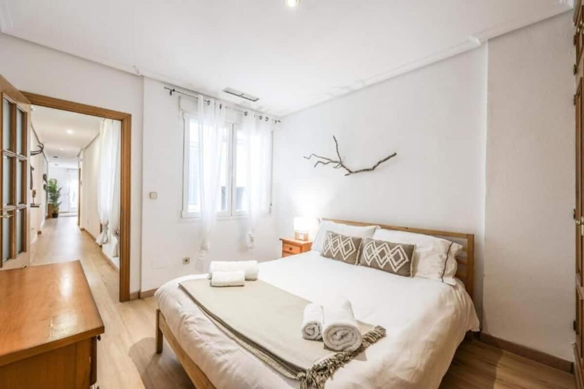 A bedroom with a bed, bedside table, and a mirror.