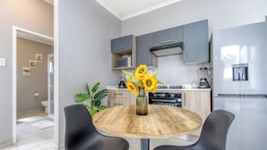 Una cocina moderna con armarios grises, un refrigerador de acero inoxidable y una mesa redonda de madera con dos sillas.