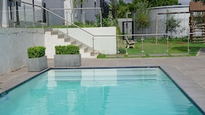 Una piscina rectangular con barandilla metálica, rodeada por una solana de concreto.