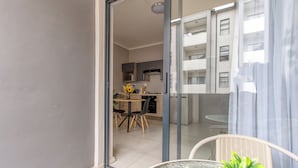 Apartamento moderno con balcón, zona de comedor y cocina visible a través de una puerta abierta.