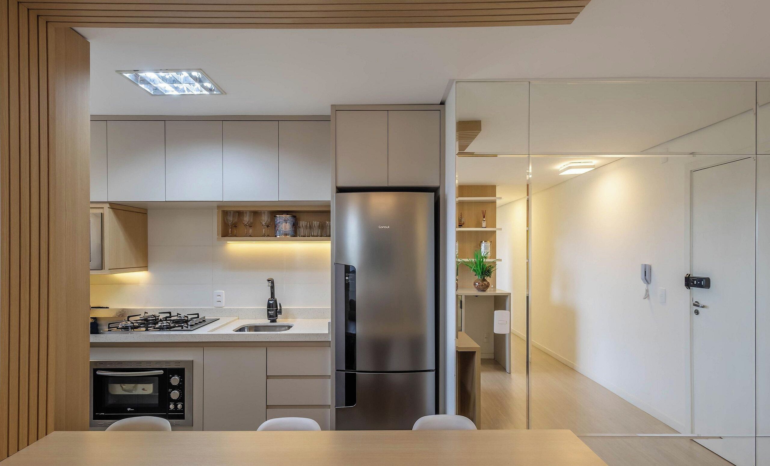 A modern kitchen with a built-in gas stove, stainless steel refrigerator, and a dining area with a table and chairs.