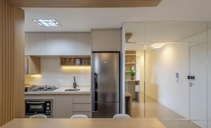 A modern kitchen with a built-in gas stove, stainless steel refrigerator, and a dining area with a table and chairs. - Apt w/ BBQ & Balcony, 400m From the Beach Leaa0506 (Picarras)