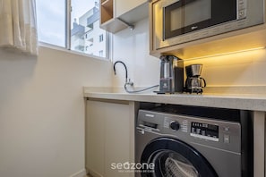 A compact kitchen with a washing machine, a coffee maker, and a microwave. - Apt w/ BBQ & Balcony, 400m From the Beach Leaa0506 (Picarras)