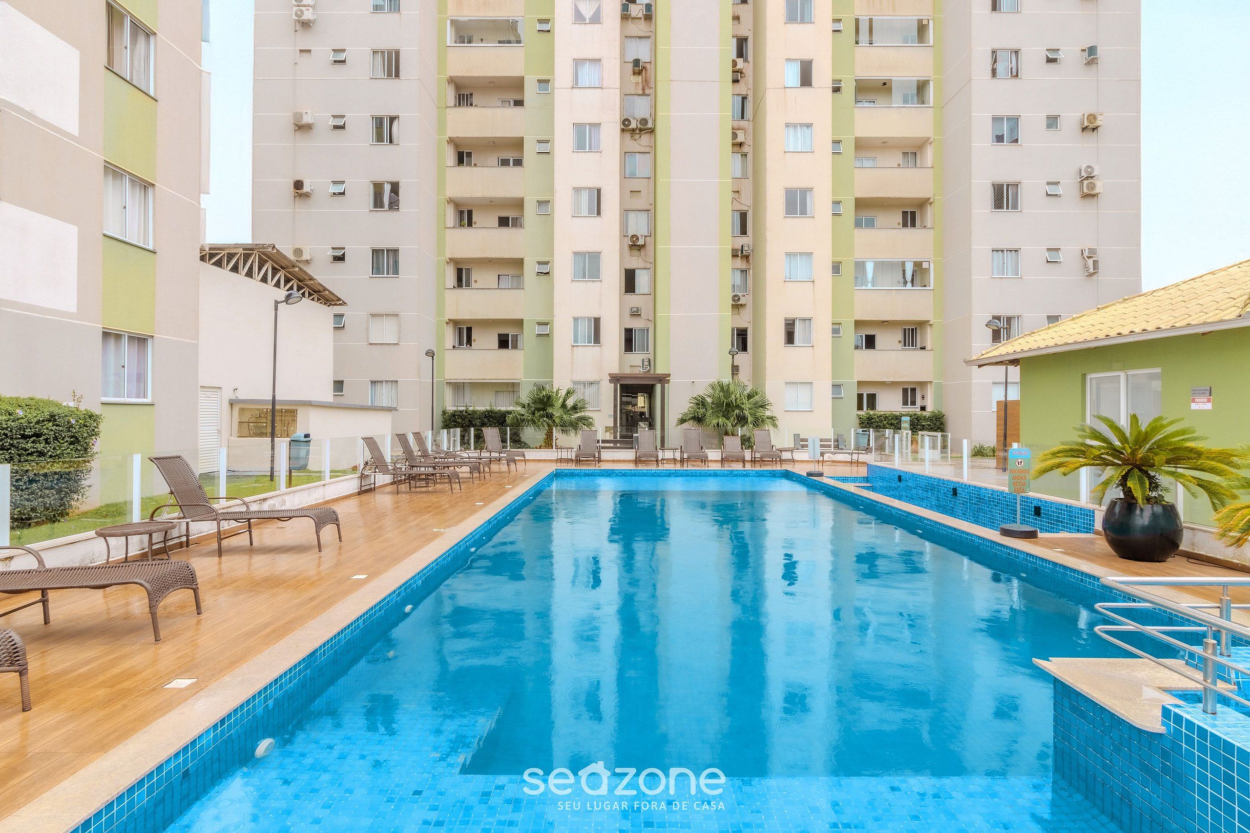 A swimming pool with lounge chairs and a building in the background.
