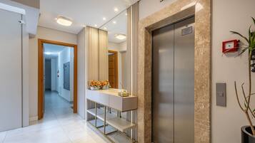 A modern elevator with a digital display, a marble wall, and a small plant.