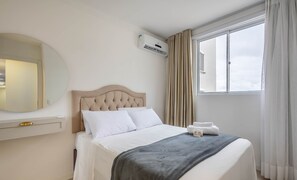 A neatly made bed with white linens, a grey throw blanket, and a small bedside table with a lamp. - Apt w/ BBQ & Balcony, 400m From the Beach Leaa0506 (Picarras)