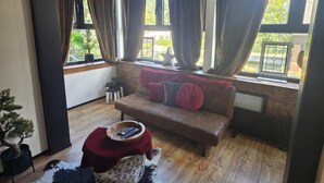 Ein modernes Wohnzimmer mit Holzboden, einer roten Sofaecke, einem Couchtisch und einer Pendelleuchte.