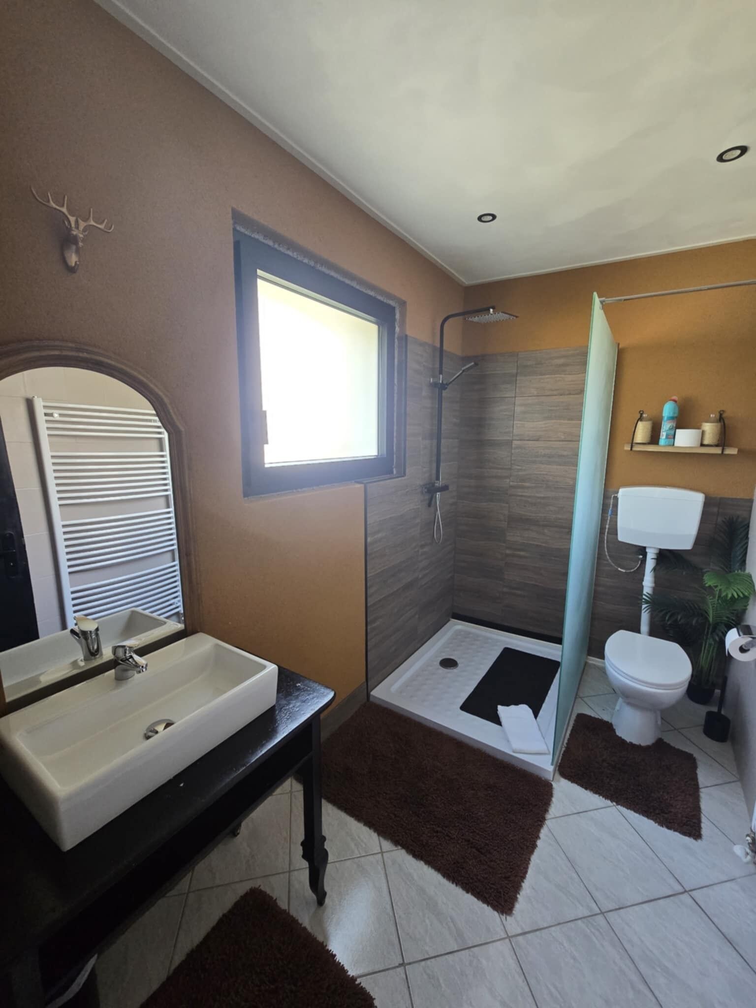 Un bagno moderno con uno specchio grande, un lavandino, una doccia e un water.